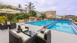 A pool area with lounge chairs, umbrellas, and a swimming pool.