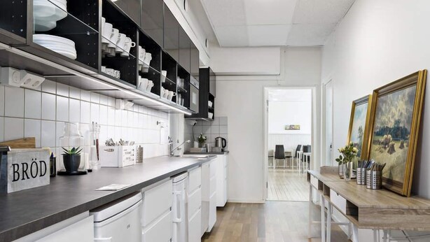 A modern kitchen with white cabinetry, a black countertop, and a wooden dining table. - Alkoven Logi (Ullared)