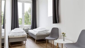A modern hotel room with two single beds, a small table, two chairs, and a window with curtains. - Alkoven Logi (Ullared)
