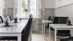 A modern dining area with a long table, black chairs, and floral curtains.