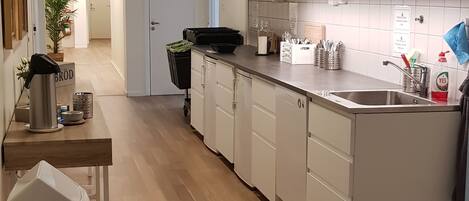 Una cocina moderna con armarios blancos, un lavamanos de acero inoxidable y una encimera negra.