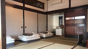 Una habitación japonesa tradicional con esteras de tatami, un futón, un armario de madera y una puerta corredera.
