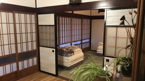 Una habitación japonesa tradicional con suelo de tatami, paneles shoji y una cama con ropa de cama doblada con cuidado.