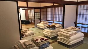 Una habitación japonesa tradicional con suelo de tatami, un biombó shoji y una pila de toallas dobladas con cuidado.