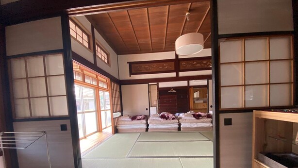 Una habitación tradicional japonesa con suelo de tatami, futón, puertas correderas y techo de madera.