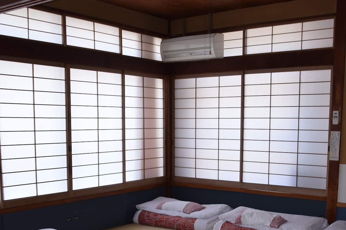 A traditional Japanese room with tatami mats, shoji screens, and futon beds.