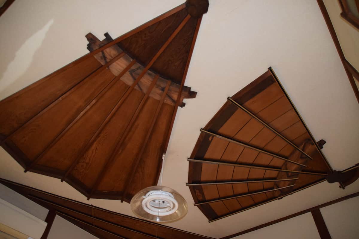 A ceiling with wooden beams and a circular skylight.
