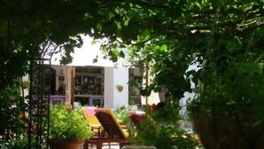 An outdoor seating area with tables and chairs, surrounded by lush greenery and potted plants.