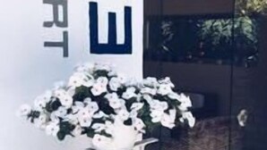 A glass door entrance with the sign "EC3 RESORT" and a white flower arrangement.