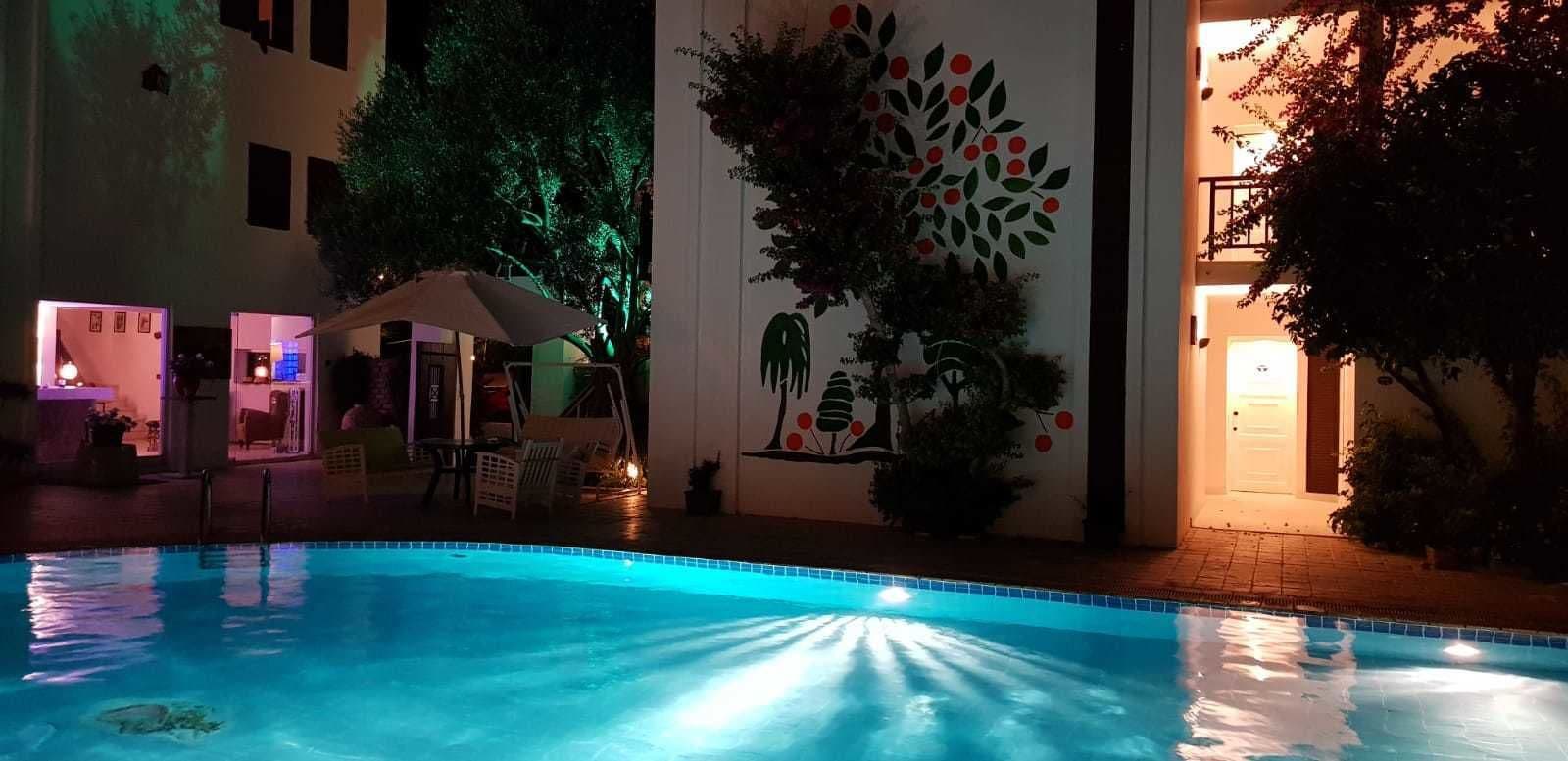 A swimming pool with a tiled edge, surrounded by lounge chairs and umbrellas.