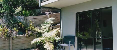 Um edifício moderno com varanda, cerca de madeira e diversas plantas.