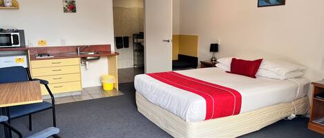 Une chambre d’hôtel comprenant un lit, un bureau, une chaise, un coin cuisine et une salle de bain.