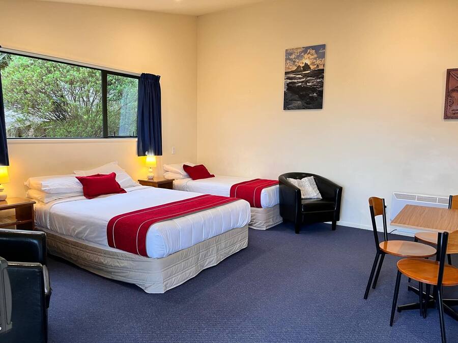 A hotel room with two beds, a desk, and a chair.