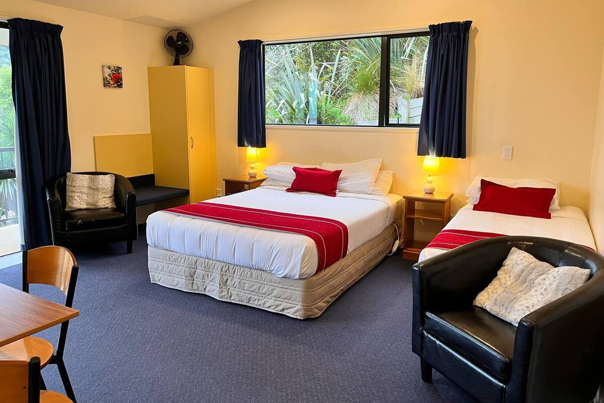 A hotel room with two beds, a desk, a chair, and a wardrobe.