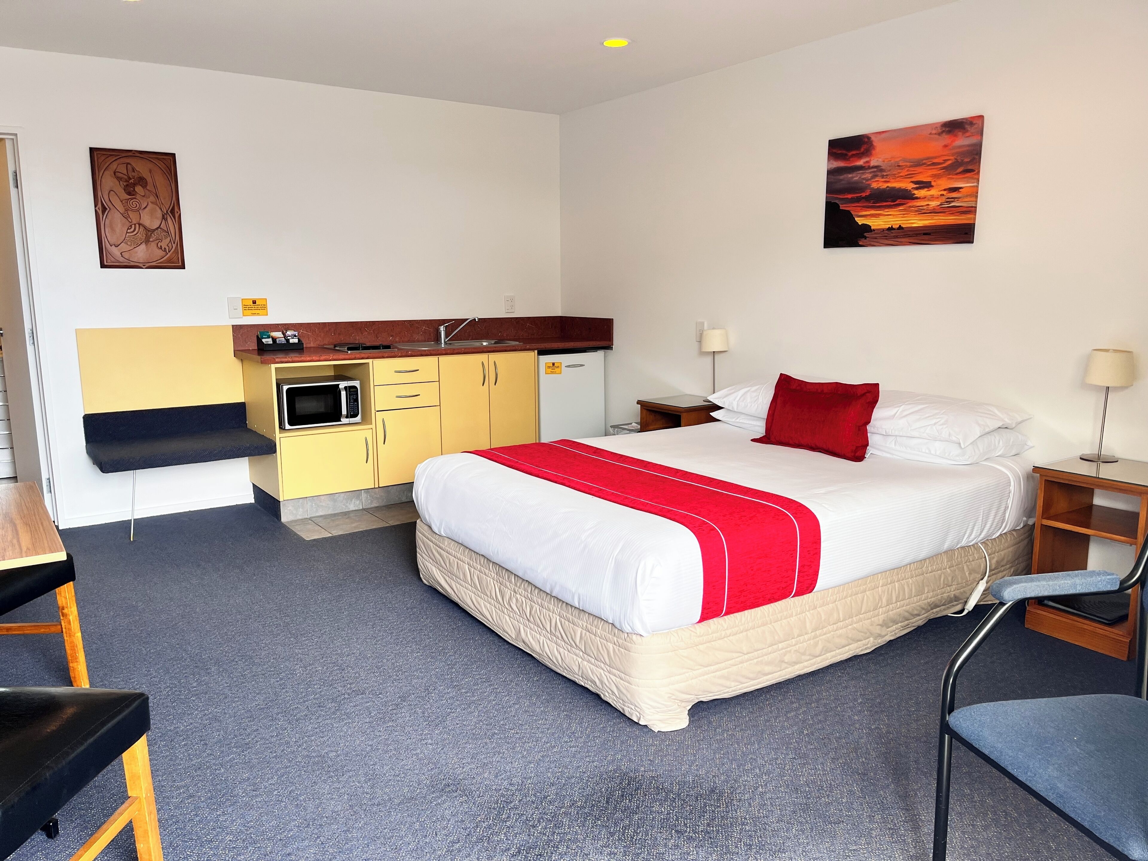 Une chambre d’hôtel avec un lit, un bureau, un four à micro-ondes, un lavabo et un tableau au mur.