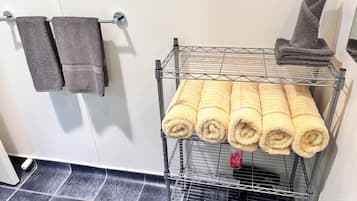 Een badkamer met een metalen droogrek met handdoeken en een handdoekhouder met twee handdoeken.