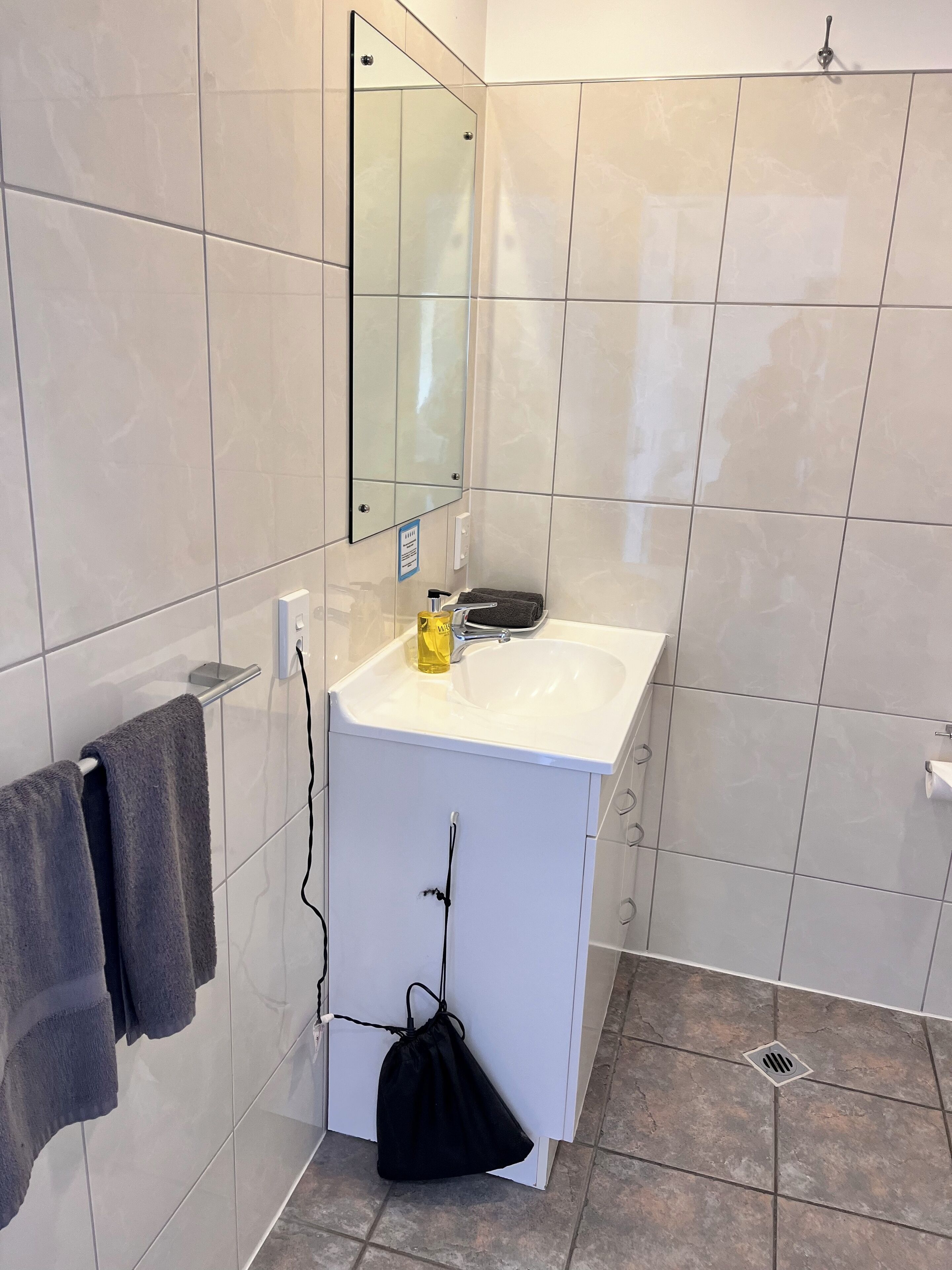 A bathroom with a white sink, a mirror, and a towel rack.