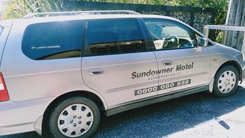 Un fourgon blanc avec l’inscription « Sundowner Motel » et un numéro de téléphone sur le côté.