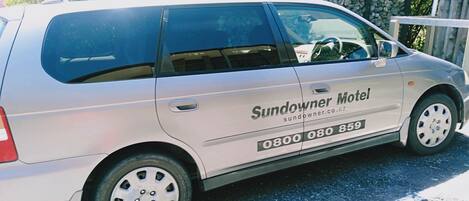 A white van with the text "Sundowner Motel" and a phone number on its side.