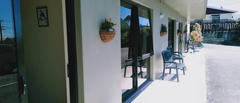 A covered outdoor seating area with chairs and potted plants.