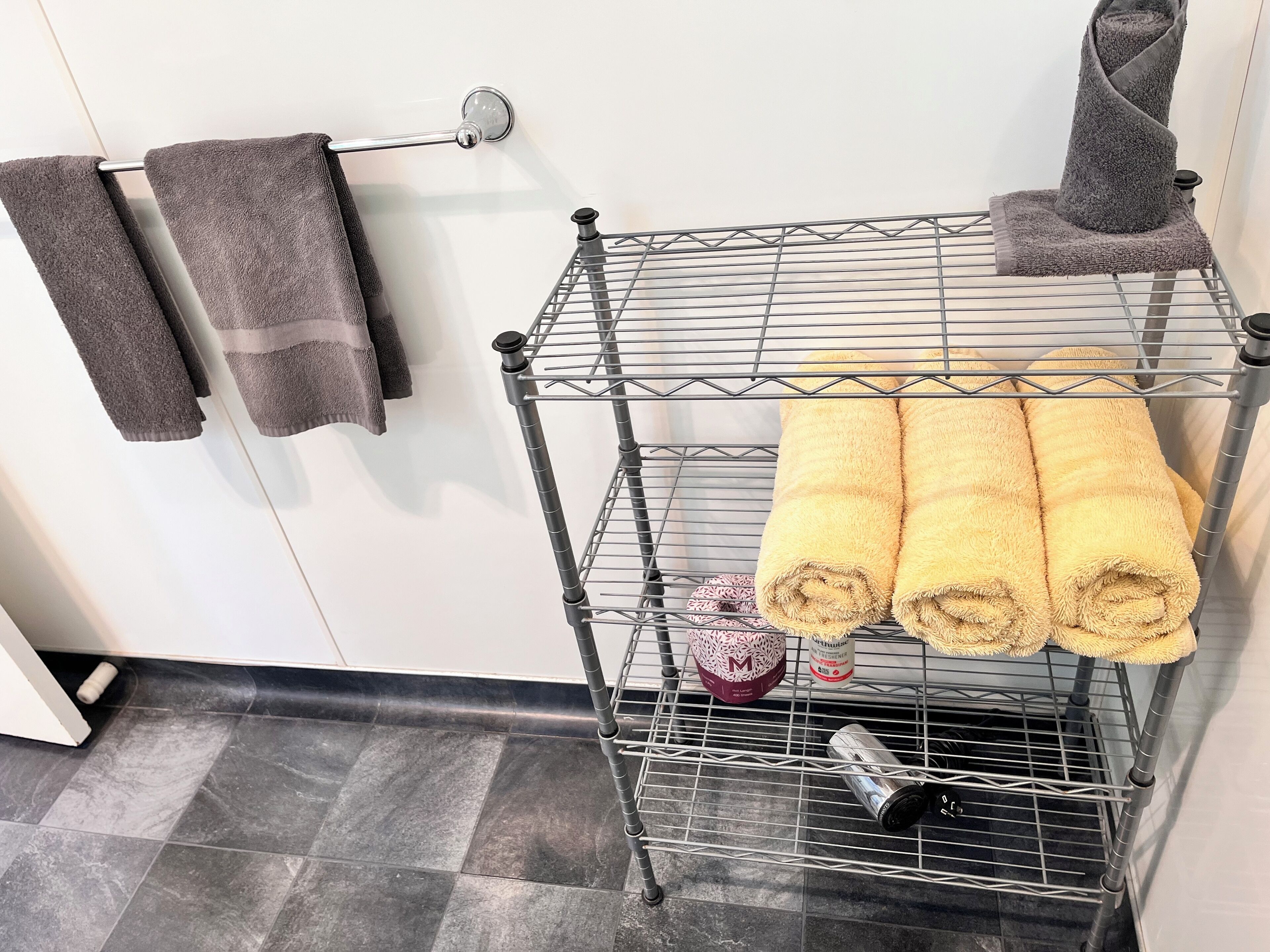 Un tendedero metálico con toallas y artículos de aseo en un baño.