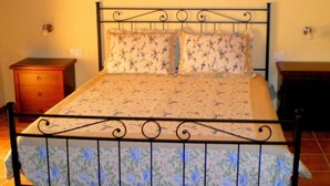 A bed with a floral-patterned mattress and matching pillows, a metal headboard, and a wooden nightstand on the left. - Villa RosaMaria (San Chirico Raparo)