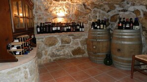 A wine cellar with stone walls, wooden barrels, and a wine rack. - Villa RosaMaria (San Chirico Raparo)