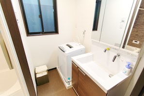 Un baño pequeño con un lavabo blanco, un espejo y una lavadora blanca.