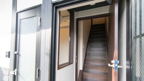 Una entrada de edificio moderna con puerta de vidrio, escalera de madera y reja de metal.