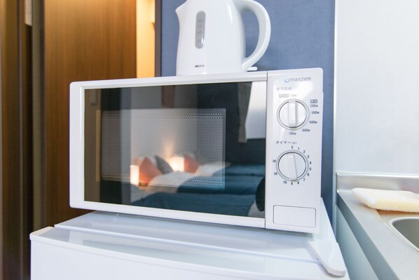 A white microwave oven with a digital display and control knobs on a white countertop.