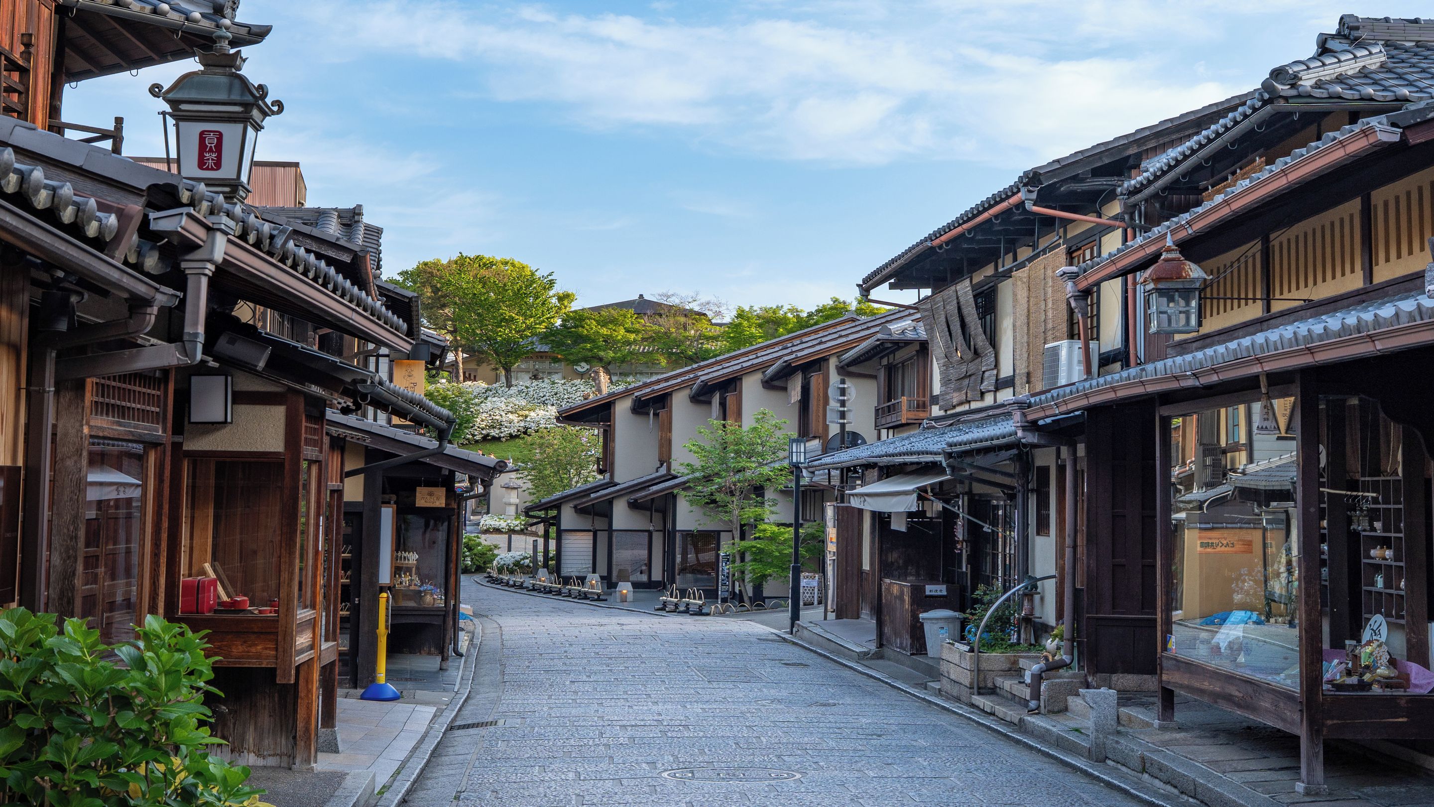Une rue typique du Japon, avec ses bâtiments en bois, son chemin pavé et un ciel dégagé.