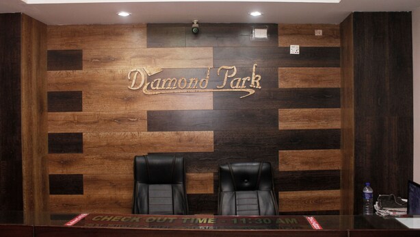 A reception desk with a wooden wall and the text "Diamond Park" above two black leather chairs. - Hotel Diamond Park (Chittagong)