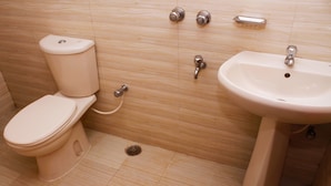 A bathroom with a toilet, sink, and a hand dryer on the wall. - Hotel Diamond Park (Chittagong)