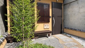 A building with a wooden bench, a sign, and a metal gate. - Stay SAKURA Kyoto Nijo Castle West I (Kyoto)