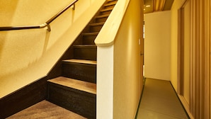 Eine Treppe mit Holzstufen und einer Handläufe, die zu einer Tür mit einer Schiebeglasplatte führt.
