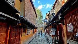 A narrow cobblestone street lined with traditional buildings, featuring wooden doors and signage in a foreign script. - Stay SAKURA Kyoto Nijo Castle West I (Kyoto)