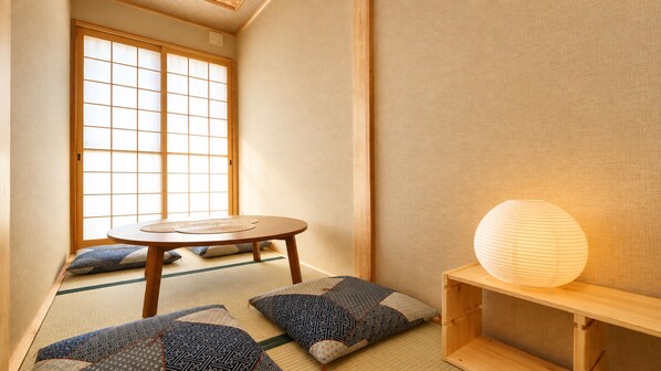 A traditional Japanese room with tatami flooring, a low wooden table, cushions, and a paper lantern. - Stay SAKURA Kyoto Nijo Castle West I (Kyoto)