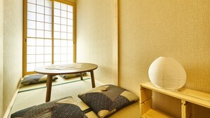 Ein traditioneller japanischer Raum mit Tatami-Böden, einem niedrigen Tisch, Kissen und einer Papierlaterne.