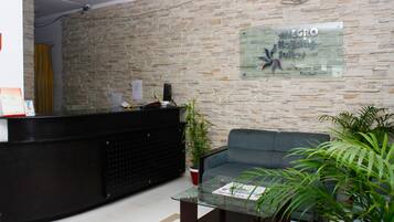 A reception area with a stone wall, a reception desk, a blue sofa, and a glass coffee table.