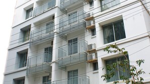 Un edificio de varios pisos con balcones, unidades de aire acondicionado y una entrada con portón.