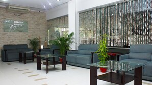Un vestíbulo moderno con un sofá azul, mesas de vidrio y plantas en macetas.