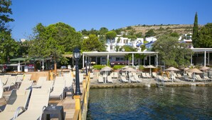 A waterfront deck with sun loungers, a covered seating area, and a view of the water. - Karianda Hotel (Bodrum)