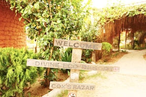 Welcome to Divine Eco Resort, situated amidst lush gardens with a brick wall backdrop.