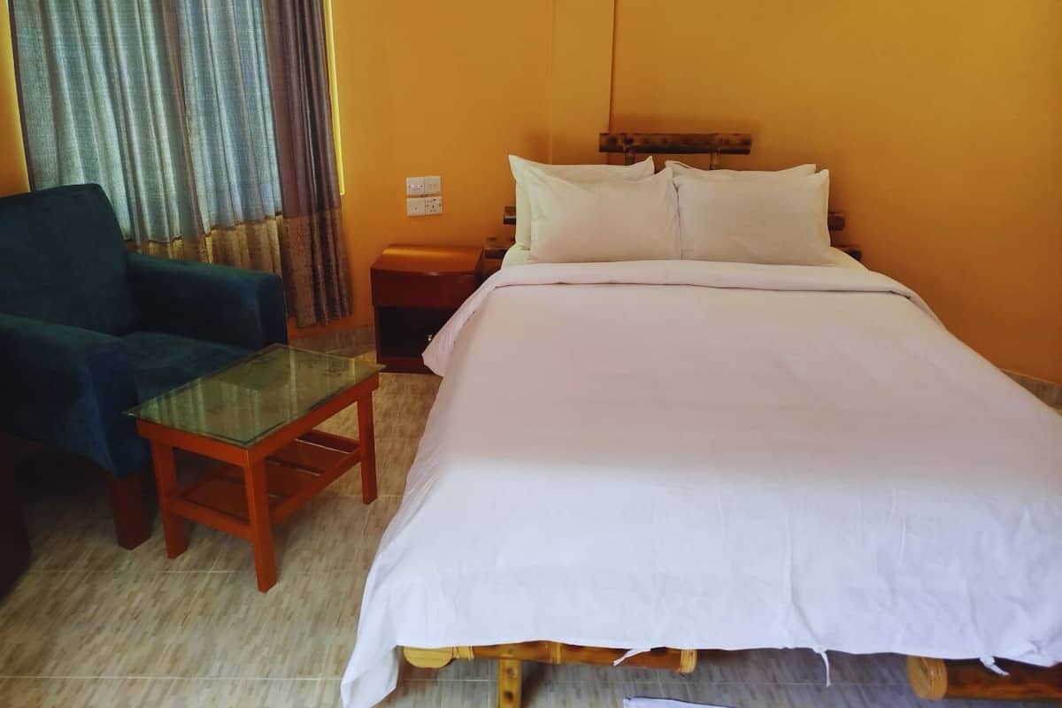 Una habitación de hotel con una cama, una mesita de noche, una silla y una mesa de vidrio.