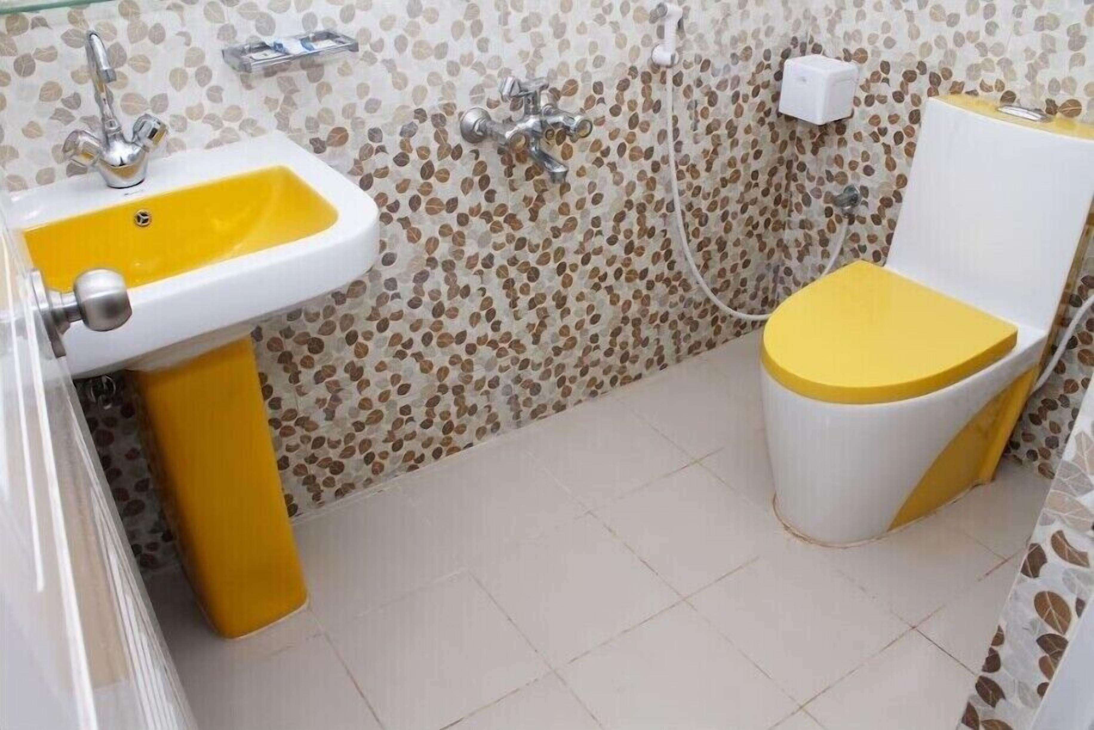 A bathroom with a yellow sink, a toilet, and a shower.