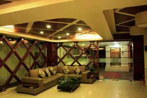 A modern lobby with a sectional sofa, a glass coffee table, and a decorative wooden partition. - Lighthouse Family Retreat (Cox's Bazar)