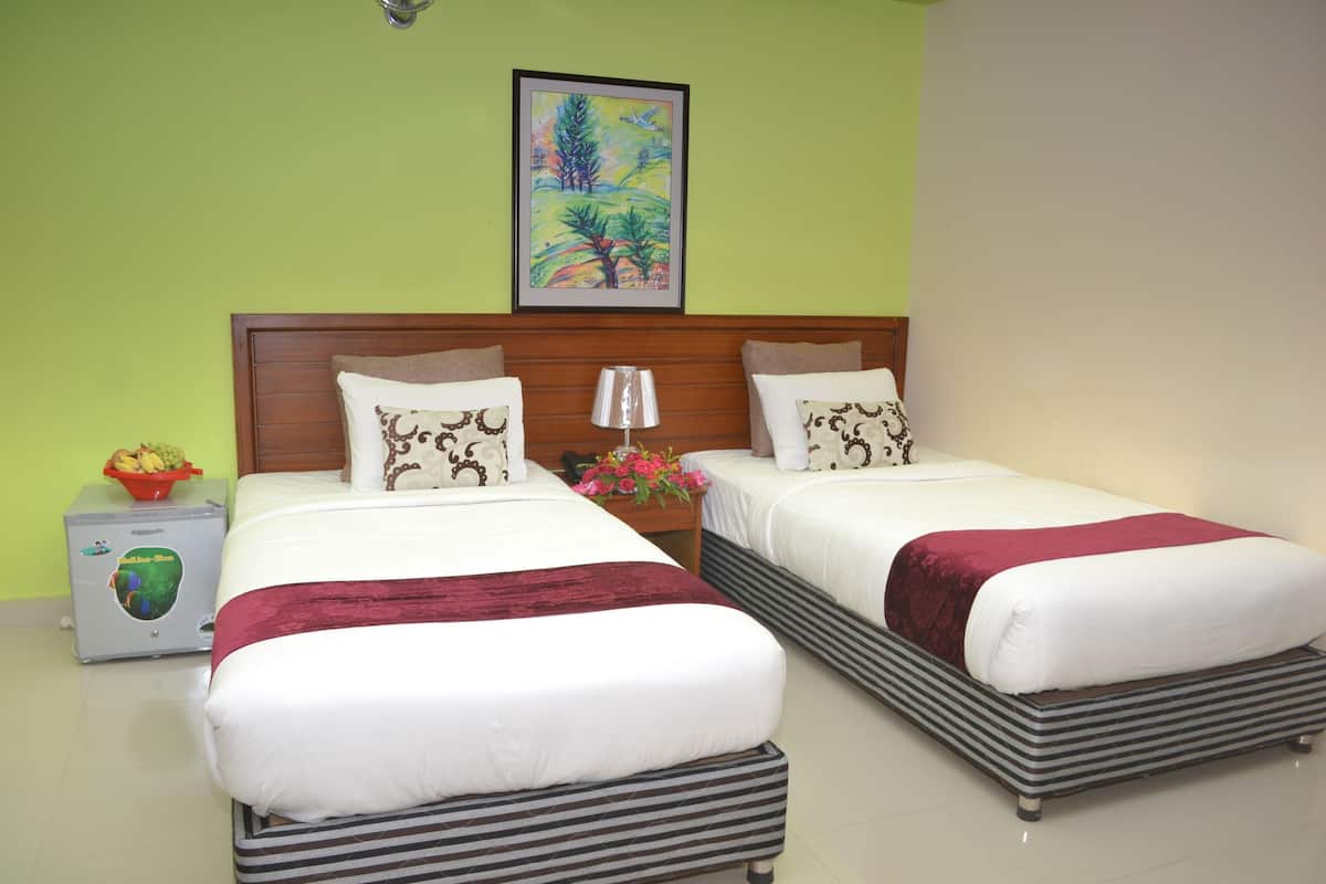 A double bed with a wooden headboard, a bedside table with a lamp, and a framed painting on the wall.