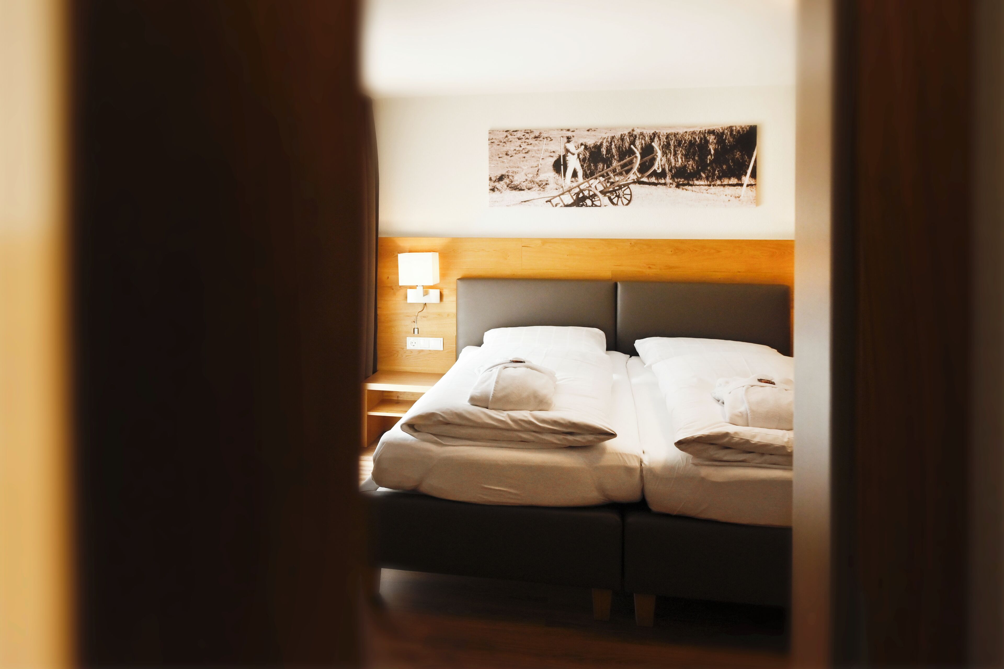 Una habitación de hotel con cama, mesita de noche, lámpara y un cuadro colgado en la pared.