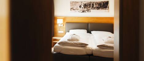 Una habitación de hotel con cama, mesita de noche, lámpara y un cuadro colgado en la pared.