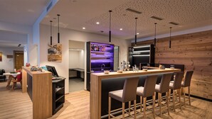 Un área de bar moderna con mostrador de madera, taburetes y un enfriador de vino.
